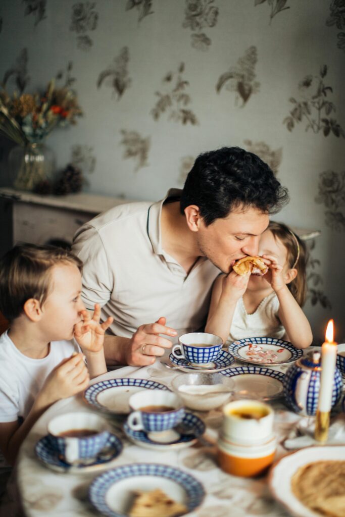 Dad having lunch with his kids and lovingly kissing his daughter's cheek
